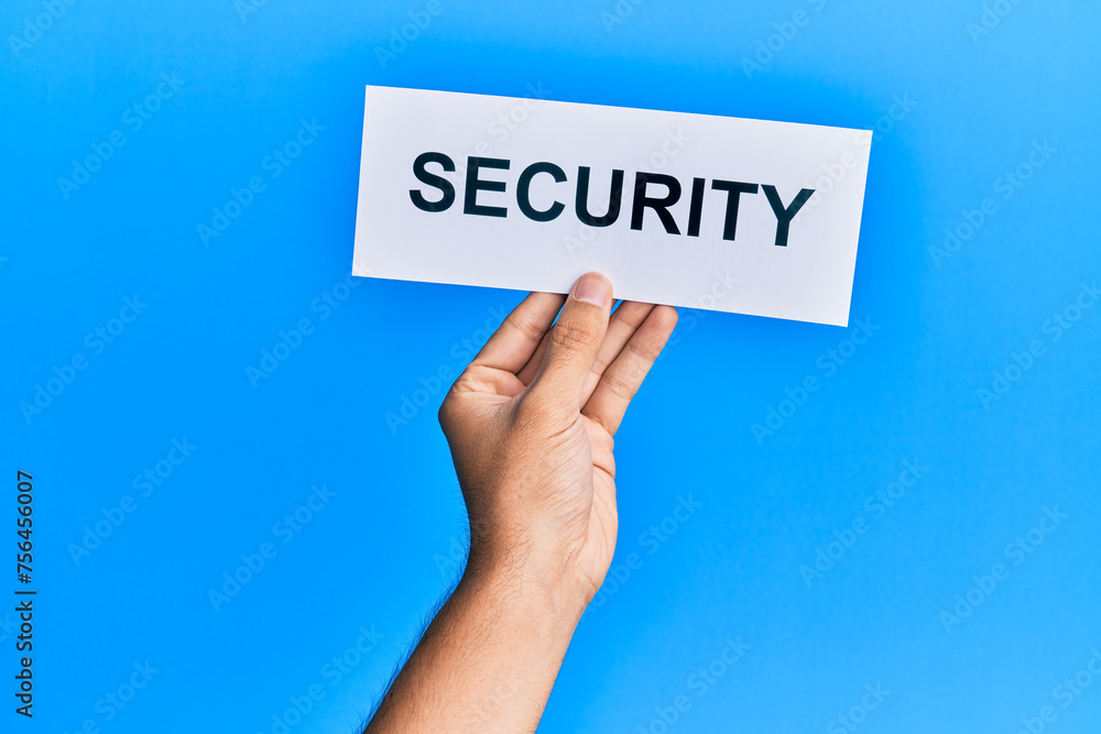 Hand of caucasian man holding paper with security word over isolated blue background Hand of caucasian man holding paper with security word over isolated blue background