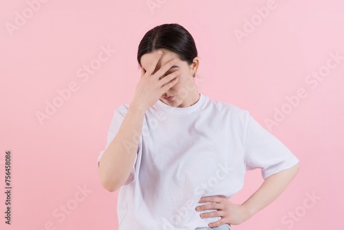Depressed attractive Caucasian young brunette woman in casual clothes making facepalm gesture, forgot about something important isolated on pink studio background.
