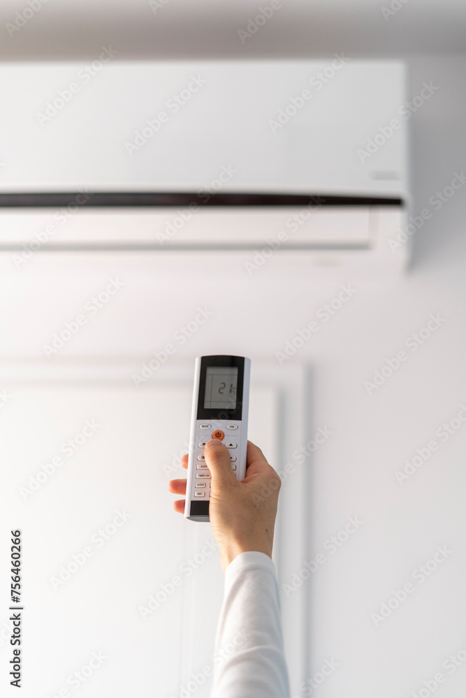 Selective focus on female hand hold remote control and turn on air conditioner Selective focus on female hand hold remote control and turn on air conditioner
