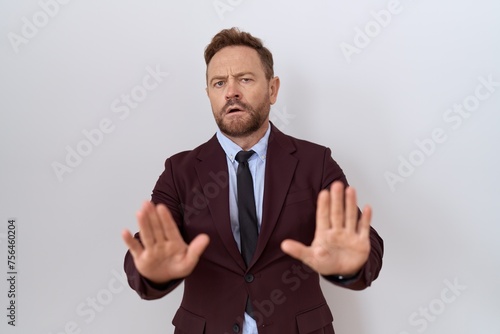 Middle age business man with beard wearing suit and tie moving away hands palms showing refusal and denial with afraid and disgusting expression. stop and forbidden.
