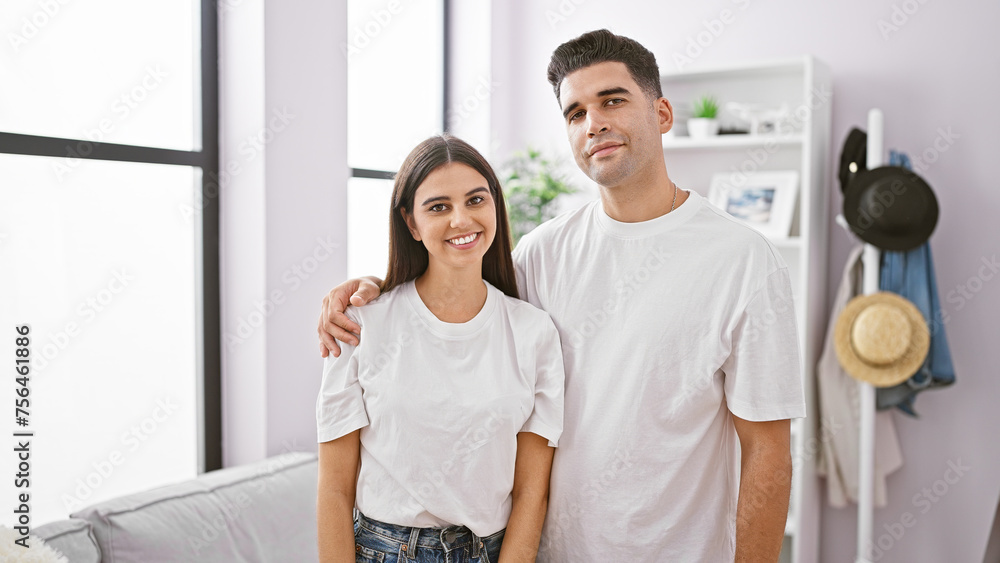 A smiling man and woman standing together in a bright, modern living room interspersed with contemporary decor A smiling man and woman standing together in a bright, modern living room interspersed with contemporary decor