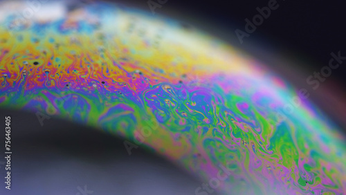 Neon paint. Holographic sphere. Psychedelic dream. Defocused rainbow color oil bubble fluid ink mix flow motion on black abstract art background.