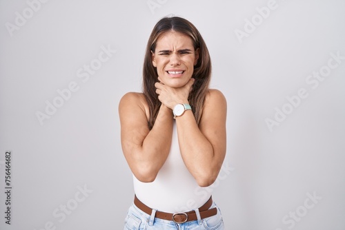 Hispanic young woman standing over white background shouting suffocate because painful strangle. health problem. asphyxiate and suicide concept.