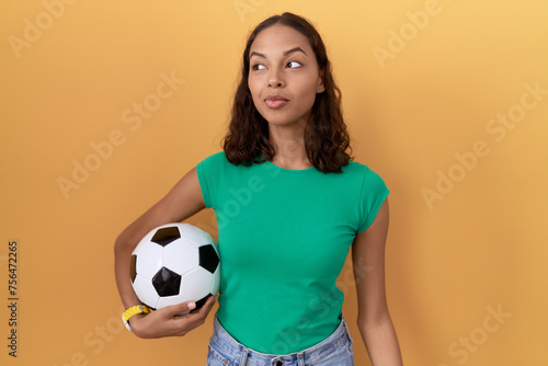 Young hispanic woman holding ball smiling looking to the side and staring away thinking. © Krakenimages.com