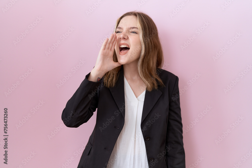 Young caucasian business woman wearing black jacket shouting and screaming loud to side with hand on mouth. communication concept. Young caucasian business woman wearing black jacket shouting and screaming loud to side with hand on mouth. communication concept.