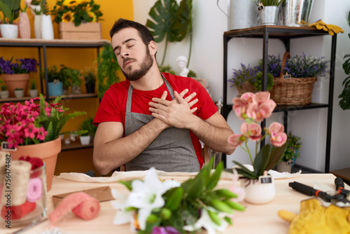 Young hispanic man working at florist shop smiling with hands on chest, eyes closed with grateful gesture on face. health concept.