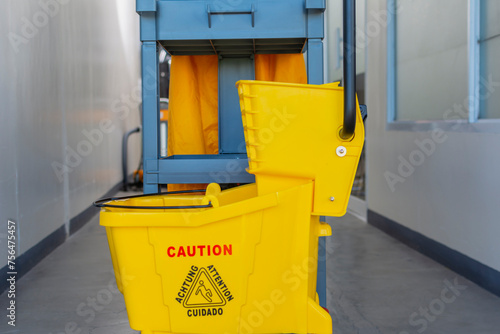 Fotografie A well-equipped janitorial cart complete with a yellow mop bucket and caution sign, ready for office cleaning tasks