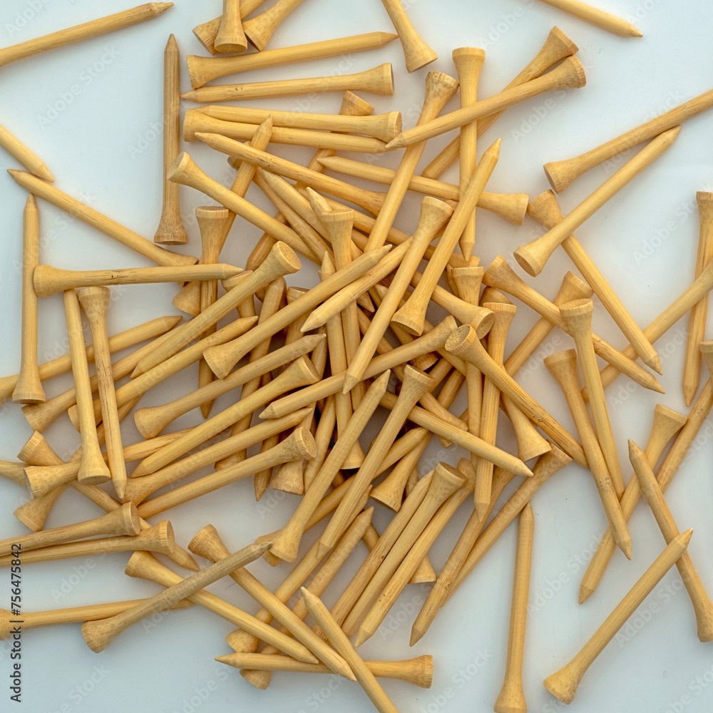 A pile of natural wood colour 70mm bamboo golf tees lying on a white surface