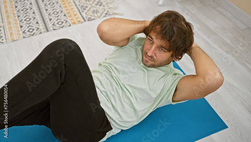 Handsome caucasian man exercising at home on a blue yoga mat in a room