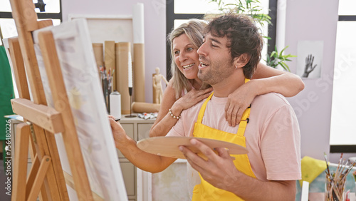 Two smiling artists, a man and a woman, confidently hugging and drawing together, blossoming creativity in an art studio