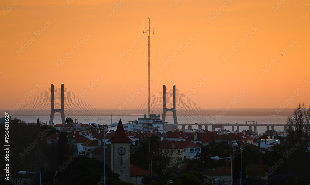 Naklejka premium Vasco da Gama bridge in Lisbon during a beautiful summer sunrise. Orange sky sunrise with landmark Vasco da Gama. Travel to Portugal.