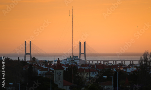Vasco da Gama bridge in Lisbon during a beautiful summer sunrise. Orange sky sunrise with landmark Vasco da Gama. Travel to Portugal.