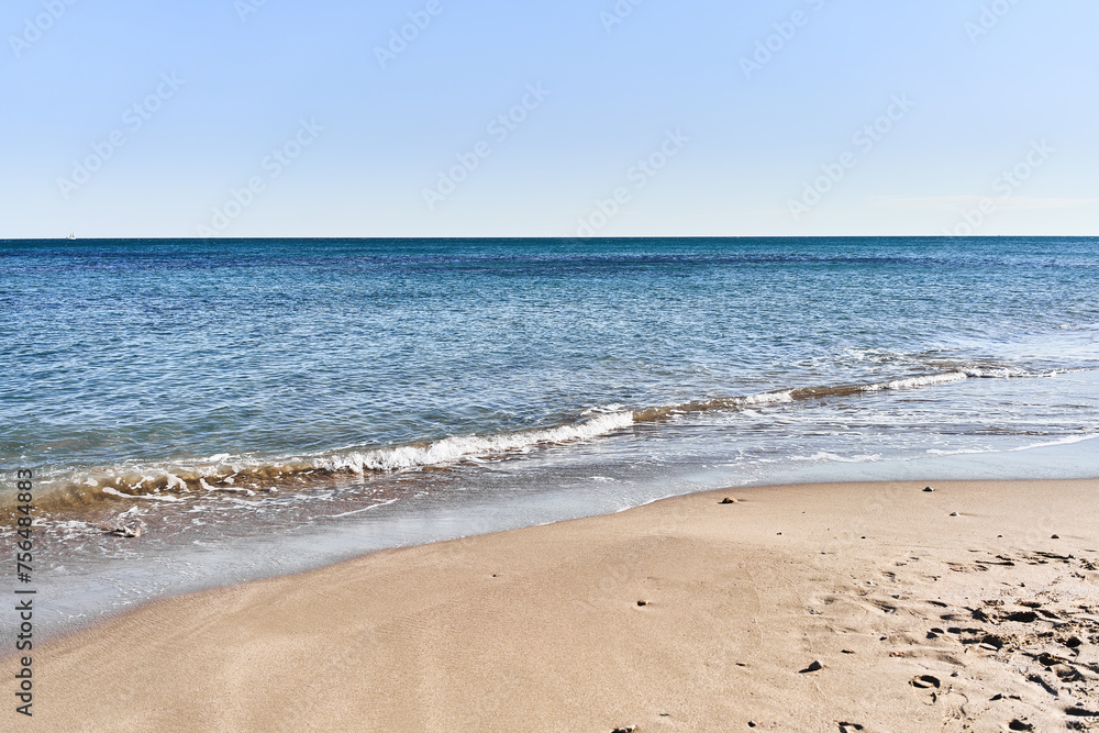 Tranquil beach scene with clear blue sky, golden sand, turquoise sea, and no people, depicting a serene holiday destination.