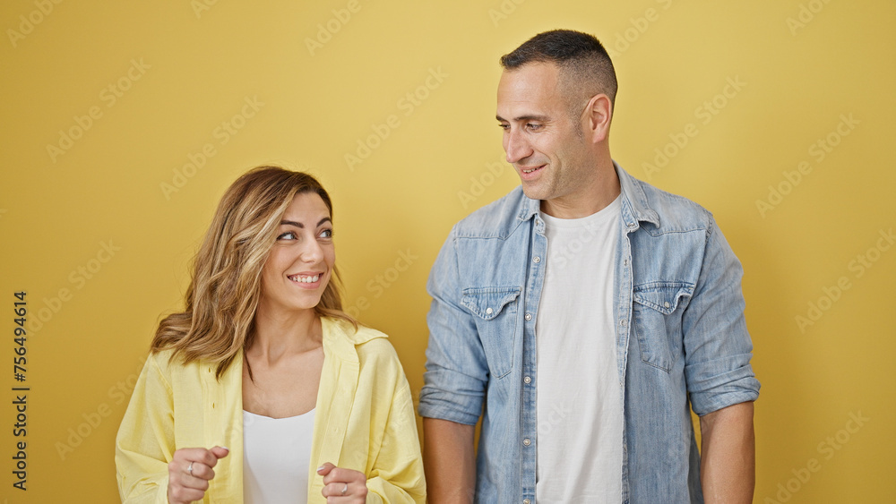 Man and woman couple smiling confident standing together over isolated yellow background Man and woman couple smiling confident standing together over isolated yellow background