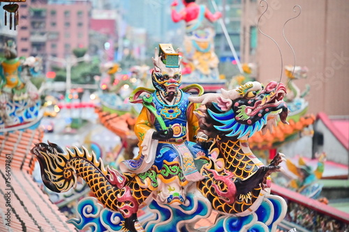 Taiwan - Jan 23, 2024: The photo shows a close-up of a detail on the roof of Songshan Ciyou Temple in Taipei, Taiwan. The detail shows a man with a dragon-like face riding on a dragon. photo