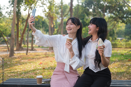 Two young businesswomen having lunch break together in the public park.