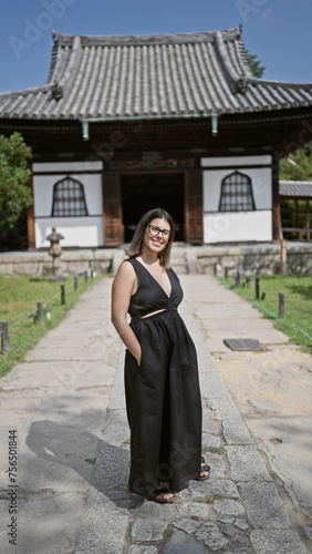 Cheerful beautiful hispanic woman, proudly posing with her glasses on, flashing a gorgeous smile at kyoto's serene kodaiji temple photo