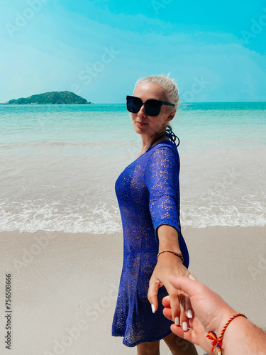 Blonde woman holding man's hand at the seaside background, followme photo photo