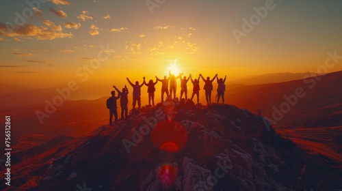 A powerful image depicting a group of people with arms raised in celebration on a mountain peak during sunset, evoking feelings of achievement, freedom, and companionship. © Riz