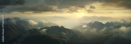 A panoramic view of a mountain range at dawn. Mist weaves through the valleys partially obscures the forested lower slopes. The rising sun illuminates the scene © Alex Shi
