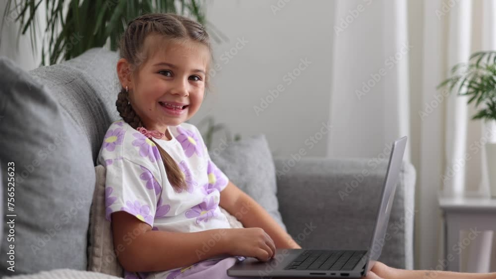 Side view of happy and smart little girl using laptop at home. Five year old girl try to use smart devise Side view of happy and smart little girl using laptop at home. Five year old girl try to use smart devise