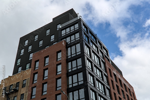 modern residential apartment building in brooklyn, new york (luxury condo high rise real estate units) co-op housing detail (windows reflecting sky, clouds) urban dwelling home new construction