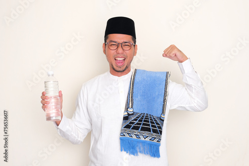 Moslem man showing his biceps muscle while holding a drinking plastic bottle photo