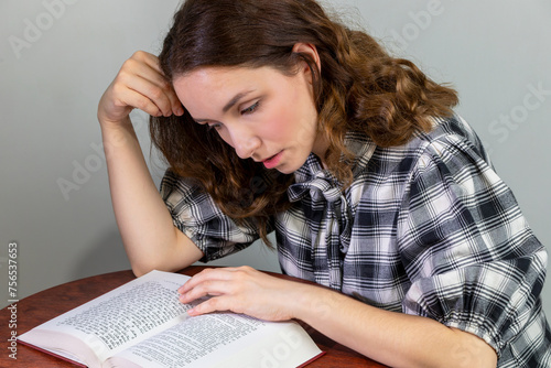 Cuadro en lienzo A young white woman is reading a bilingual, Polish-Hebrew edition of the Torah