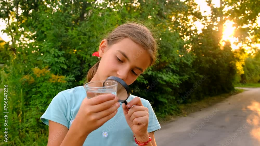 a child looks at a glass of water with a magnifying glass. selective focus. a child looks at a glass of water with a magnifying glass. selective focus.
