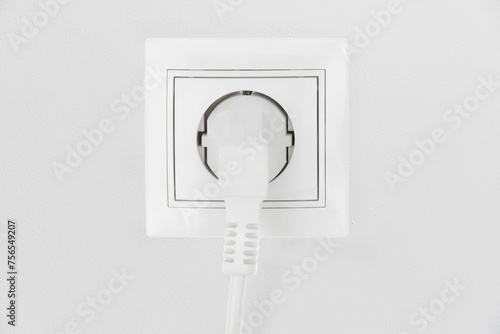 Power electric sockets on a white wall. electric cord plugged into a white electricity rosette on white background. outlet on the white wall