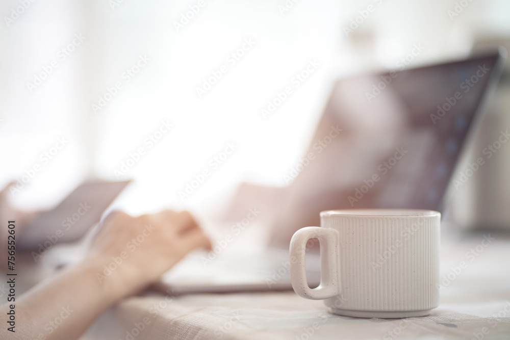 Close up cup of hot coffee with blurred hands using laptop and mobile on table at office. Close up cup of hot coffee with blurred hands using laptop and mobile on table at office.