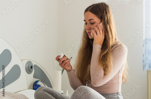 Wellness and dieting young woman,consulting with her doctor using mobile phone, searching prescription on medicine label about vitamins information, holding bottle of food supplement.