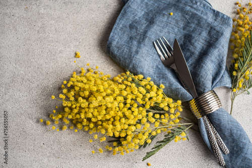 Close-up of a cutlery setting with yellow mimosa flowers on a table