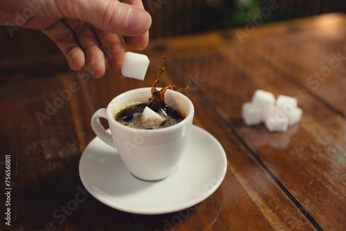 Zuckerwürfel werden in Tasse Kaffee geworfen photo