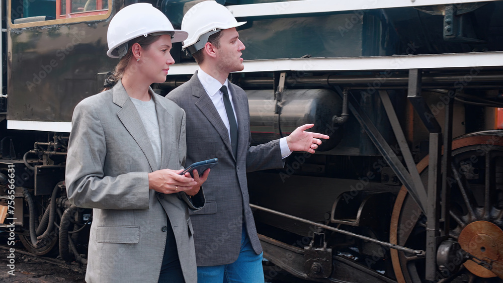 Young caucasian engineer man and woman in suit checking train with tablet in station, team engineer inspect system transport, technician examining infrastructure, transportation and industry. Young caucasian engineer man and woman in suit checking train with tablet in station, team engineer inspect system transport, technician examining infrastructure, transportation and industry.