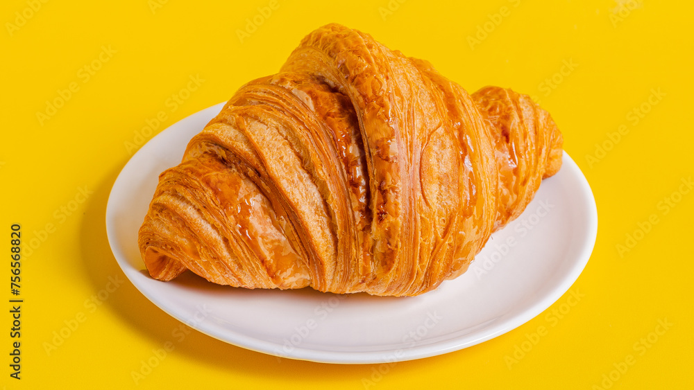 French croissant on plate isolated on yellow background French croissant on plate isolated on yellow background