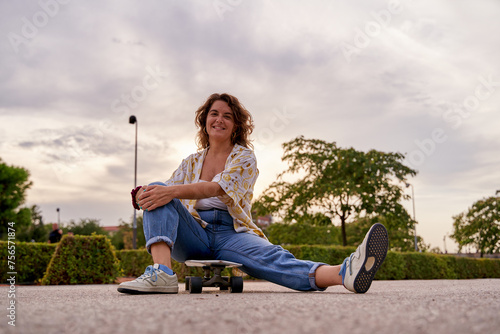 young Caucasian woman sitting on the skateboard