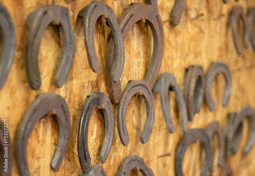 Horseshoes hang on the wall. Farm forge. Forged metal horse hoof guard