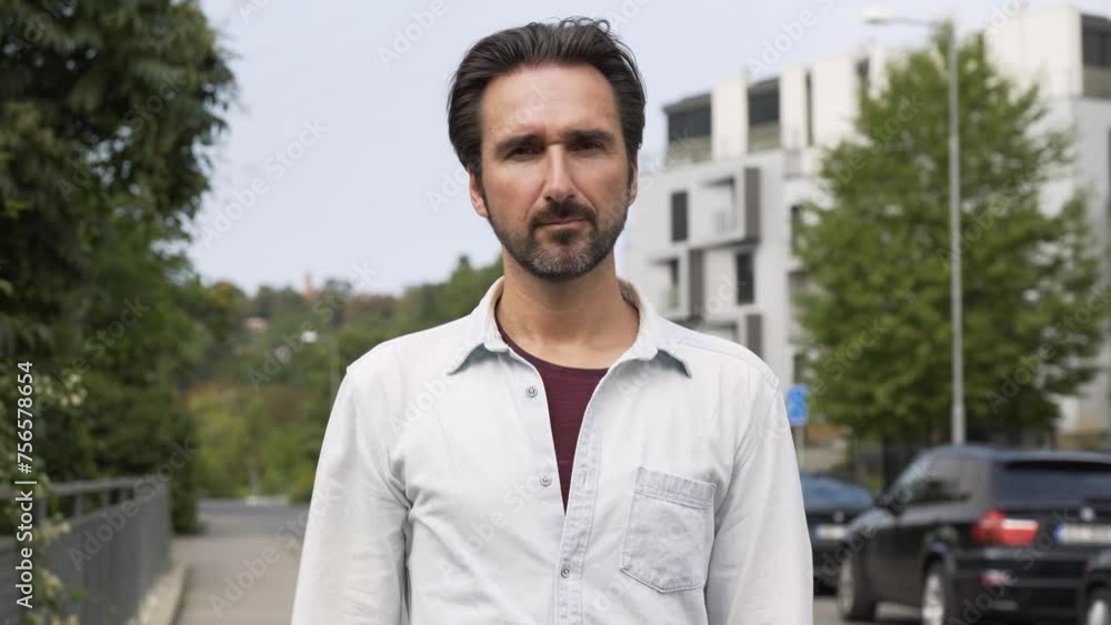 A handsome Caucasian man shakes his head and shows a thumb down to the camera in a suburban street A handsome Caucasian man shakes his head and shows a thumb down to the camera in a suburban street