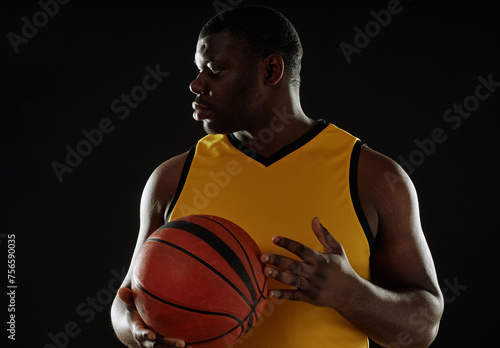 Backlit shot of muscular basketball player holding ball against black background copy space © Seventyfour