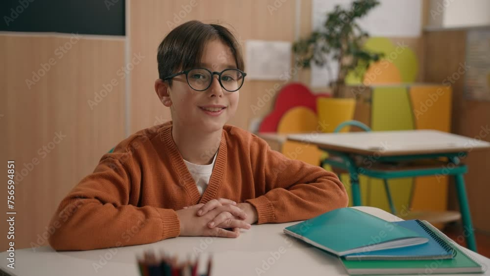 Portrait little smiling Caucasian boy in eyeglasses healthy son looking at camera sitting at table primary school classroom smile kid schoolboy child baby pupil student studying education at desk Portrait little smiling Caucasian boy in eyeglasses healthy son looking at camera sitting at table primary school classroom smile kid schoolboy child baby pupil student studying education at desk