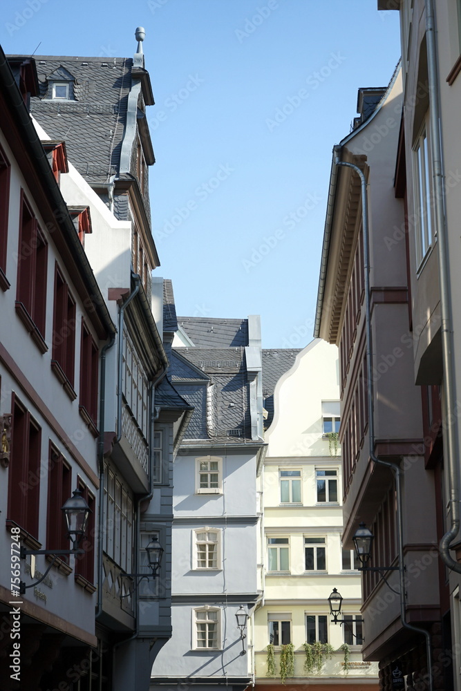 Obraz premium Neu erbaute Häuserzeile im historischen Stil für Touristen mit Gastronomie, Boutiquen und Geschäften vor blauem Himmel im Sonnenschein in der neuen Altstadt am Römerberg in Frankfurt am Main in Hessen