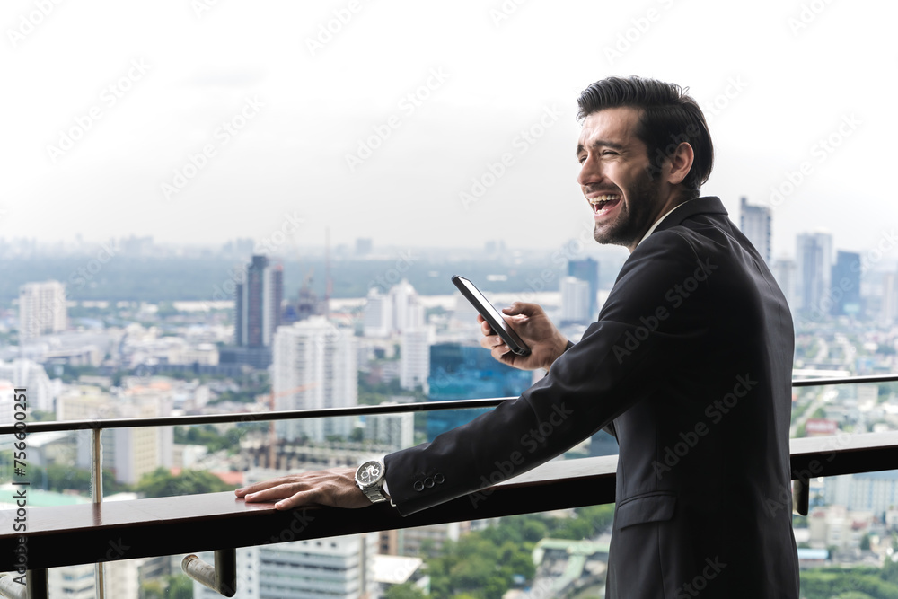 Handsome Indian businessman using smartphone in high building balcony in downtown city Handsome Indian businessman using smartphone in high building balcony in downtown city