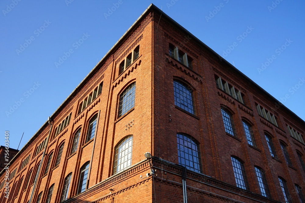 Fototapeta premium Fensterfront einer alten Fabrik mit Fassade aus Backstein vor blauem Himmel im Sonnenschein in der Klassikstadt im Stadtteil Fechenheim in Frankfurt am Main in Hessen