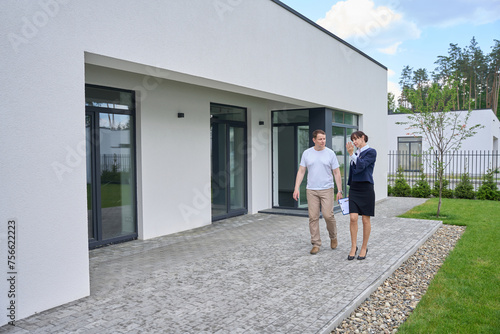 Female client manager communicates with a buyer outside new house © Svitlana