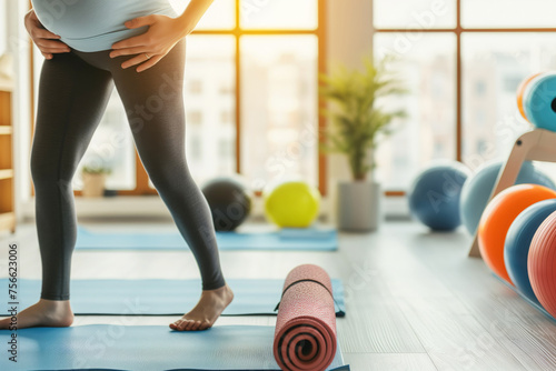 Pregnant woman standing on yoga mat in fitness studio