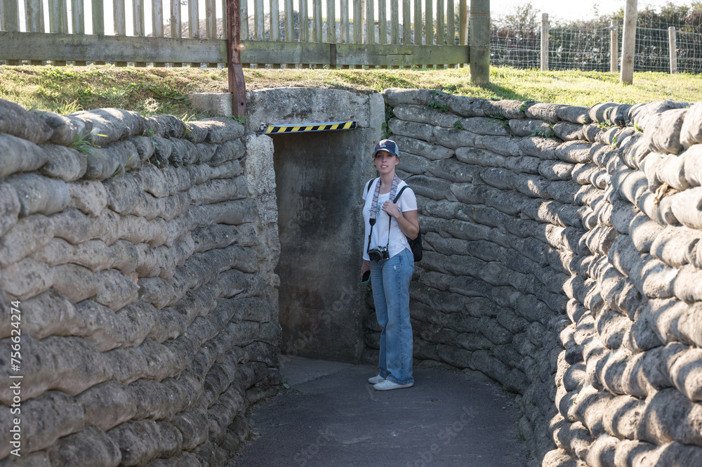 A young girl with a cap, backpack and camera visiting the German World War II bunkers at the Museum and the Merville Battery site. It's in the underground sandbag passageway. A young girl with a cap, backpack and camera visiting the German World War II bunkers at the Museum and the Merville Battery site. It's in the underground sandbag passageway.