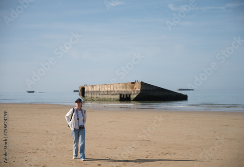 Young girl with backpack sightseeing along the coast of Normandy, France where Operation Overlord D-Day occurred with the remains of Mulberry Harbors photo