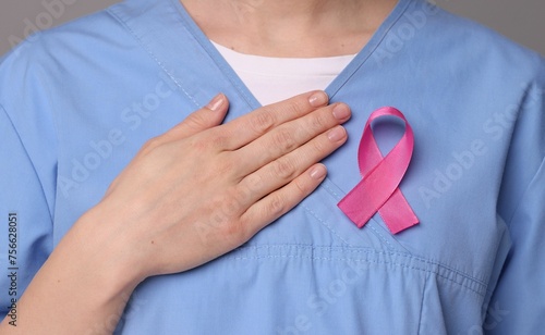 Mammologist with pink ribbon on gray background, closeup. Breast cancer awareness