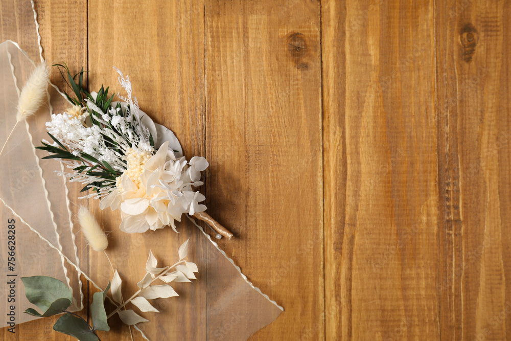 Fototapeta premium Stylish boutonniere and ribbon on wooden table, top view. Space for text
